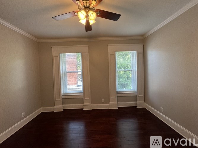 A room with a ceiling fan and two windows.