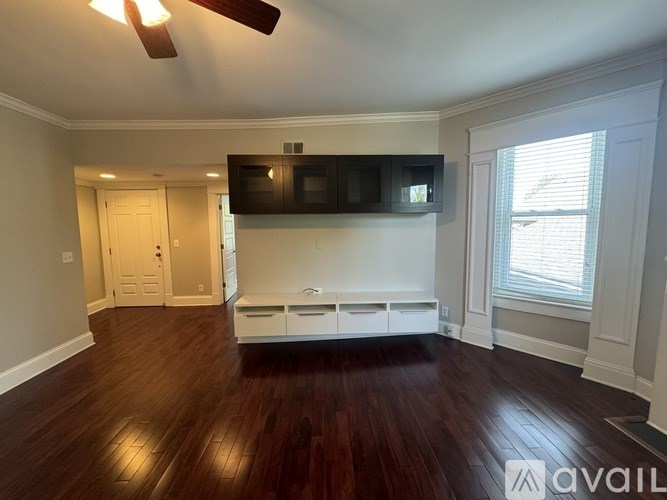A living room with a dark wood floor and a white ceiling fan.