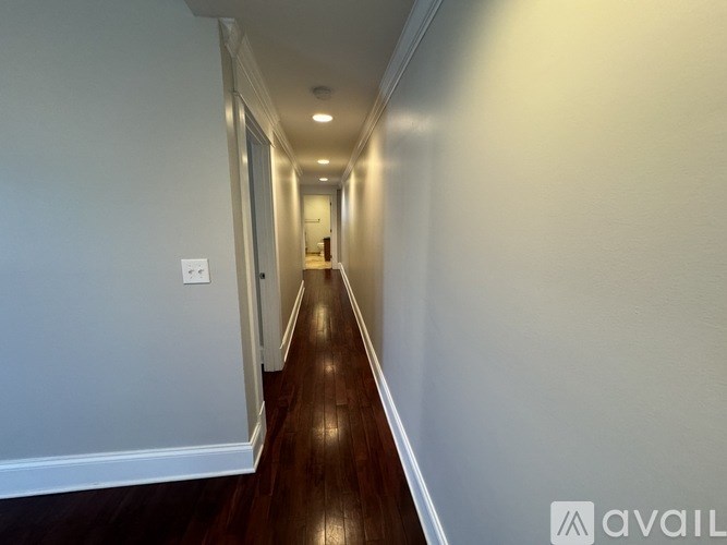 A long hallway with wooden floors and white walls.