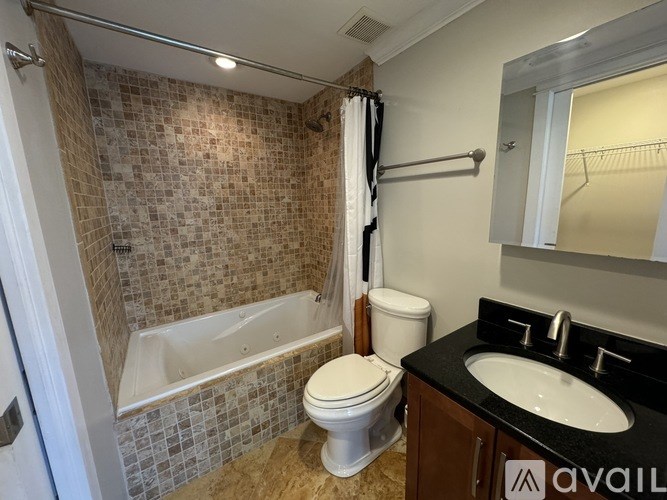A bathroom with a tiled shower, toilet, and sink.