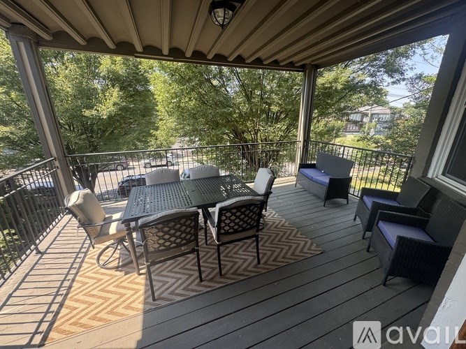 A patio with a table and chairs is surrounded by a black railing.