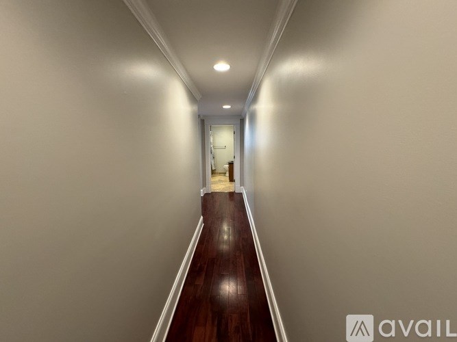 A long hallway with a wooden floor and white walls.