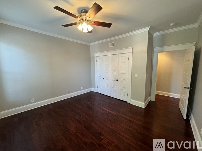 A room with a ceiling fan and wooden floors.