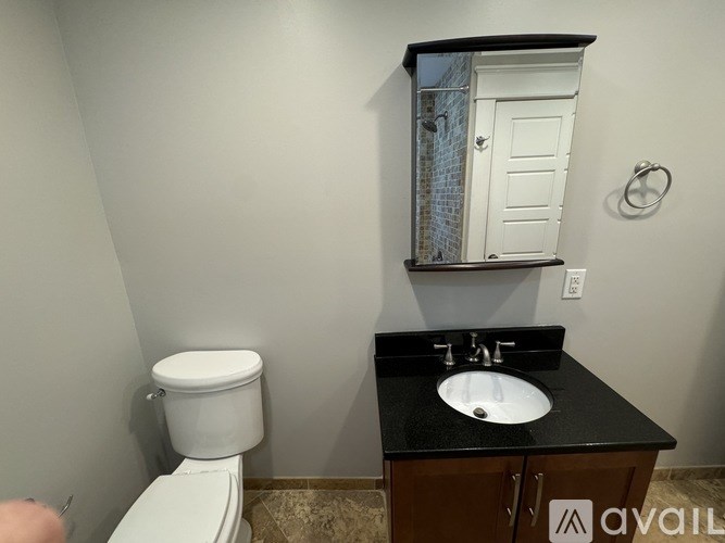 A bathroom with a toilet, sink, and mirror.