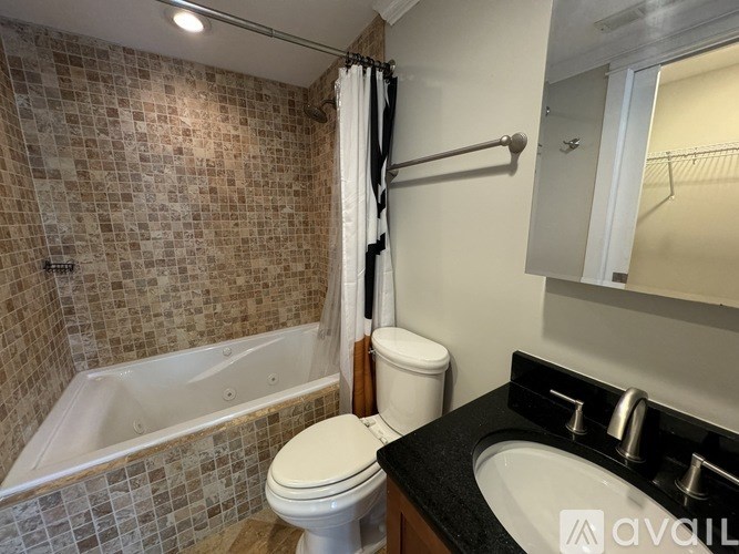 A bathroom with a tiled shower, toilet, and sink.