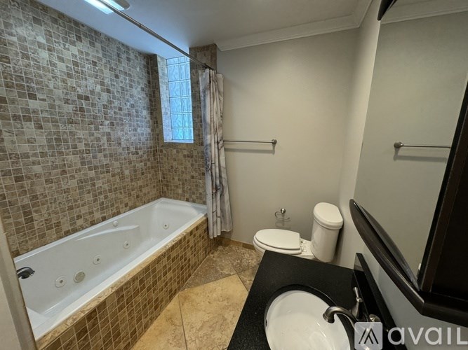 A bathroom with a tiled wall and a bathtub.