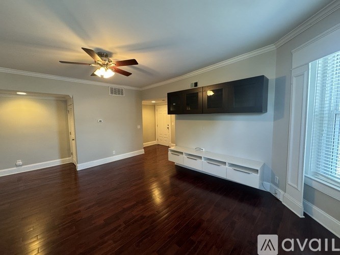 A spacious room with wood flooring and a ceiling fan.