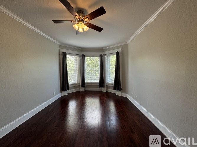A room with a ceiling fan and wooden flooring.