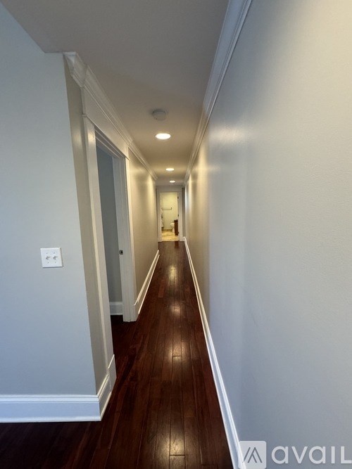 A long hallway with wood floors and white walls.
