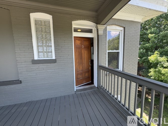 A wooden door is on the porch of a house.