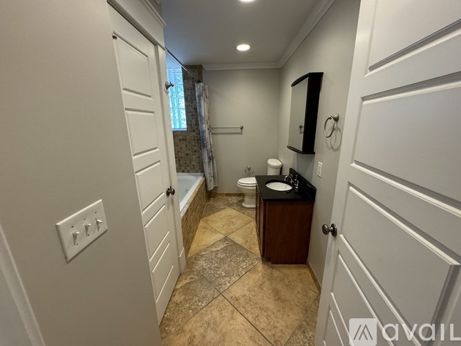 A bathroom with a toilet, sink, and mirror.