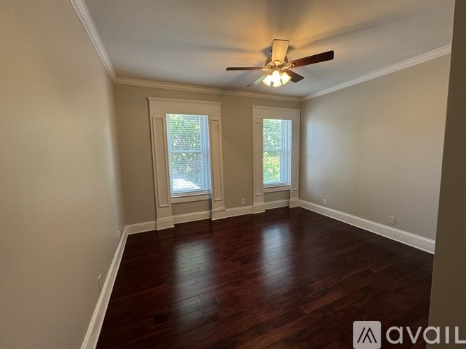 A room with a ceiling fan and two windows.