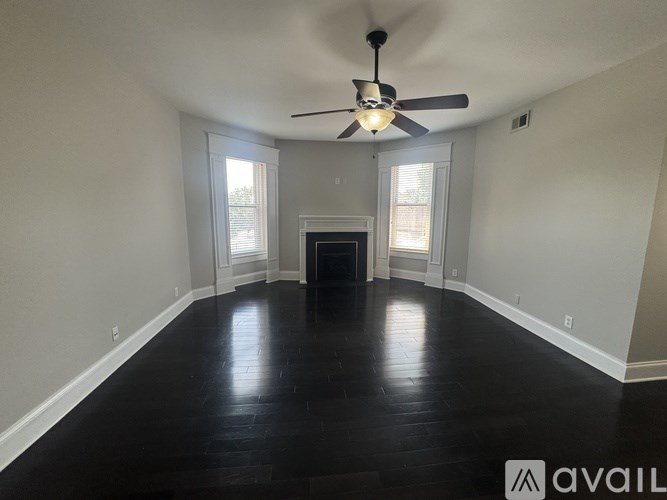 A spacious room with a fireplace and a ceiling fan.