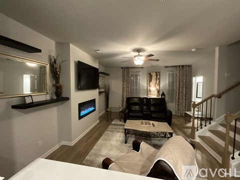 A living room with a black couch and a television on the wall.