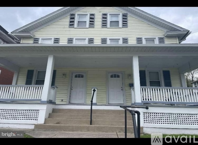 A two-story house with a porch and a white door.
