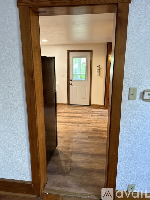 A wooden doorway leading to a room with a white door.
