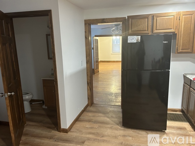 A black fridge in a room with wooden floors and white walls.