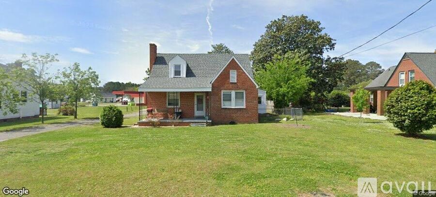A red brick house with a white roof and a green lawn in front.