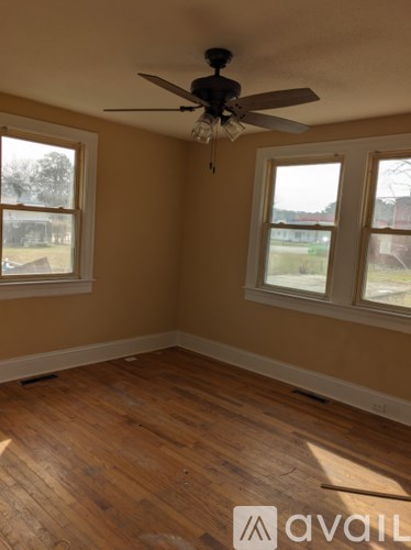 A room with a ceiling fan and two windows.