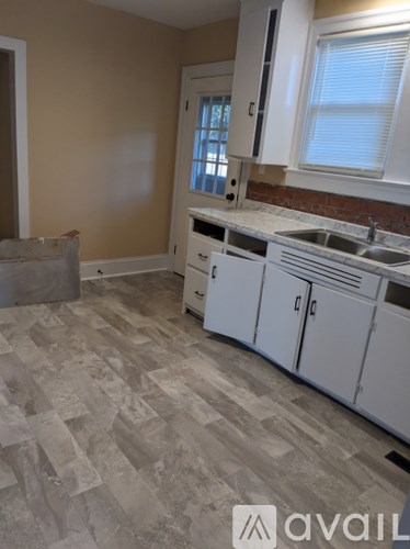 A kitchen with white cabinets and a tiled floor.