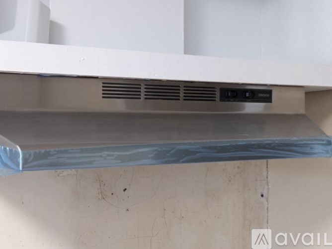 A white shelf with a silver bar and ventilation grill.