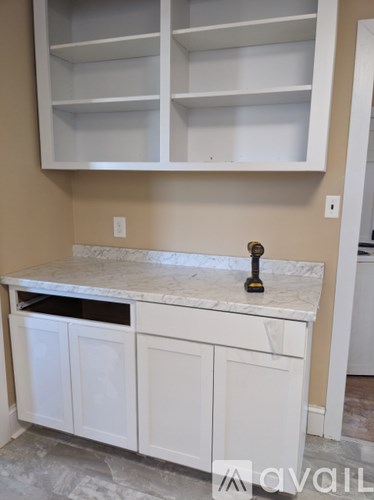 A kitchen counter with a marble top and white cabinets.