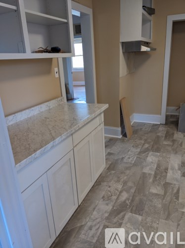 A kitchen with white cabinets and a marble countertop.