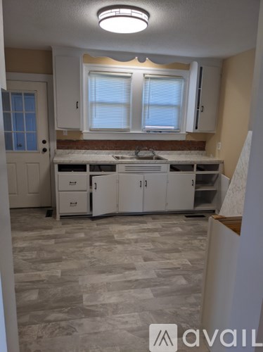 A kitchen with a tile floor and a window above the sink.