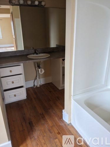 A bathroom with a white tub and wooden floors.