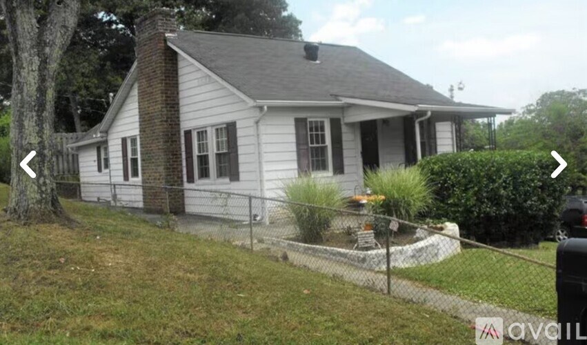 A white house with a grey roof and a black fence.