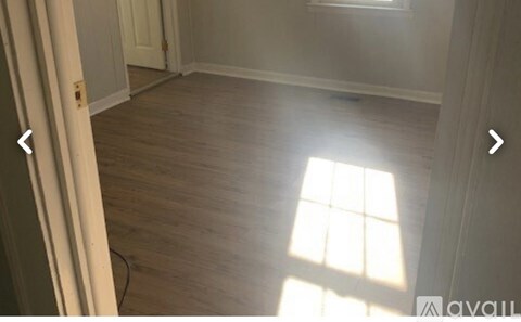 A room with wooden flooring and a window letting in sunlight.