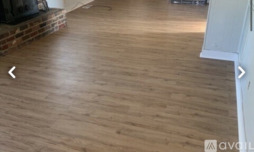 A room with wooden flooring and a fireplace.