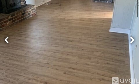 A room with wooden flooring and a fireplace.