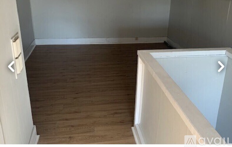 A room with wooden flooring and white walls.