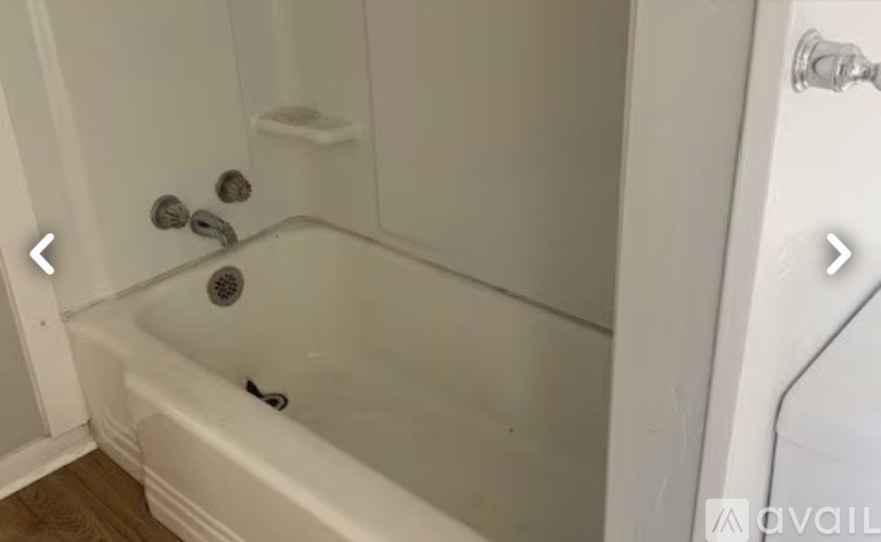 A white bathtub with a shower head and faucet.