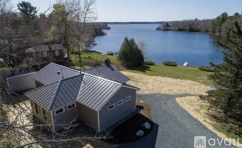 A house with a grey roof is surrounded by nature.