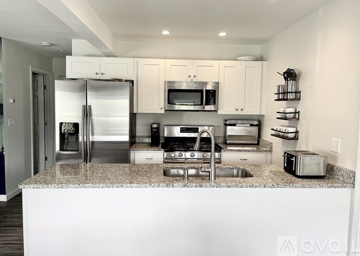 A modern kitchen with granite countertops and stainless steel appliances.