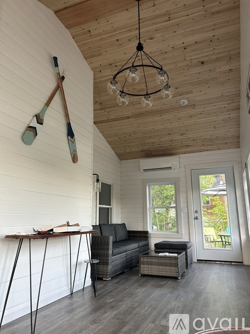 A room with a wooden ceiling and a grey sofa.