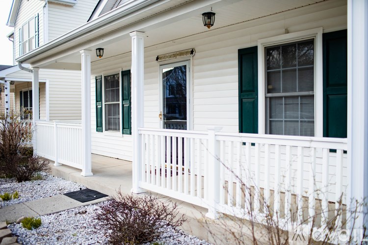 A white house with green shutters and a white porch.