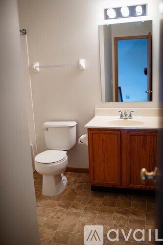 A bathroom with a toilet, sink and mirror.