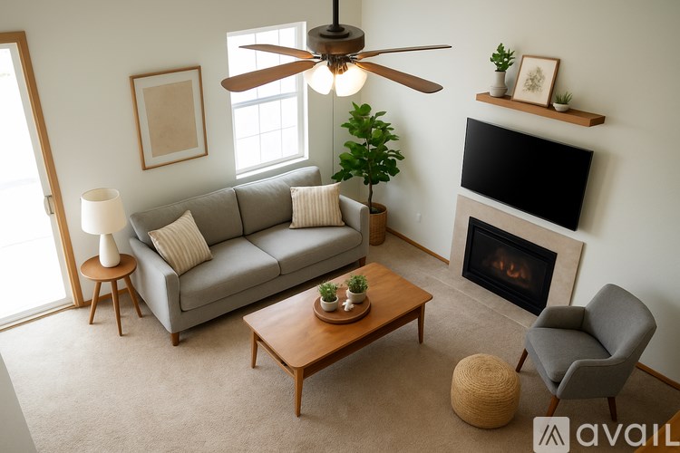 A living room with a grey couch, a wooden coffee table, a grey armchair, a fireplace, and a ceiling fan.