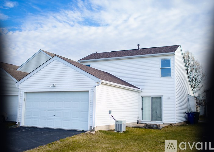 A white house with a garage door and a window on the side.
