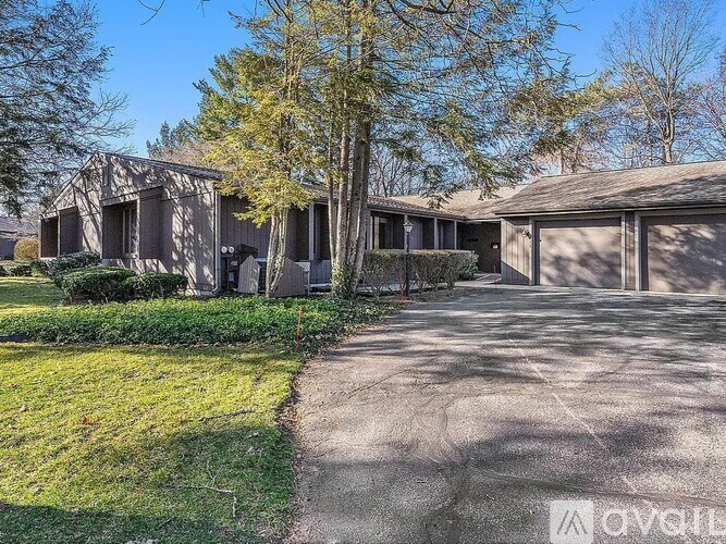 A house with a driveway and a tree in front.