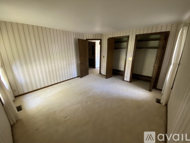 A room with wooden flooring and striped wallpaper with two doors.