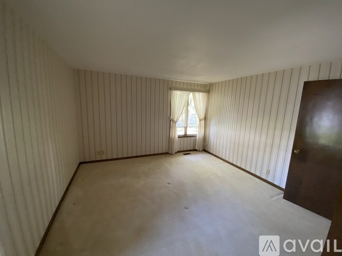 A room with wooden walls and a window with a white curtain.