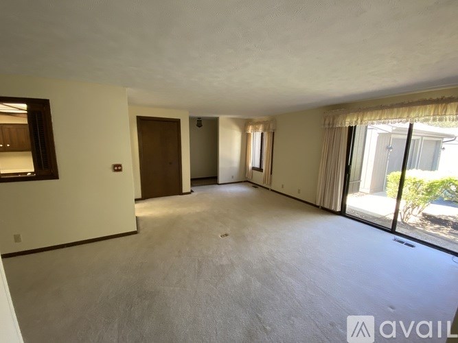 A spacious living room with a sliding glass door leading to a patio.