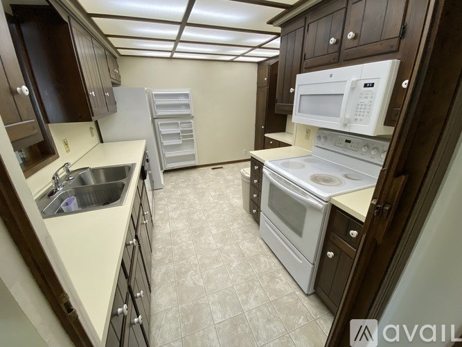 A kitchen with white appliances and brown cabinets.