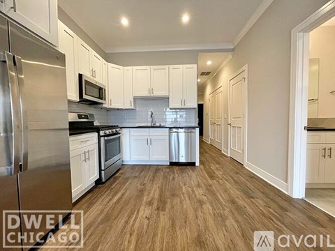 A kitchen with white cabinets and a stainless steel refrigerator.