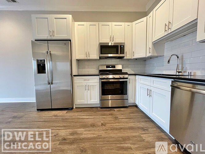 A kitchen with white cabinets and a stainless steel refrigerator.