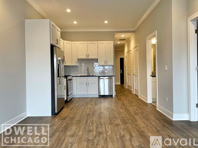 A kitchen with white cabinets and a wooden floor.